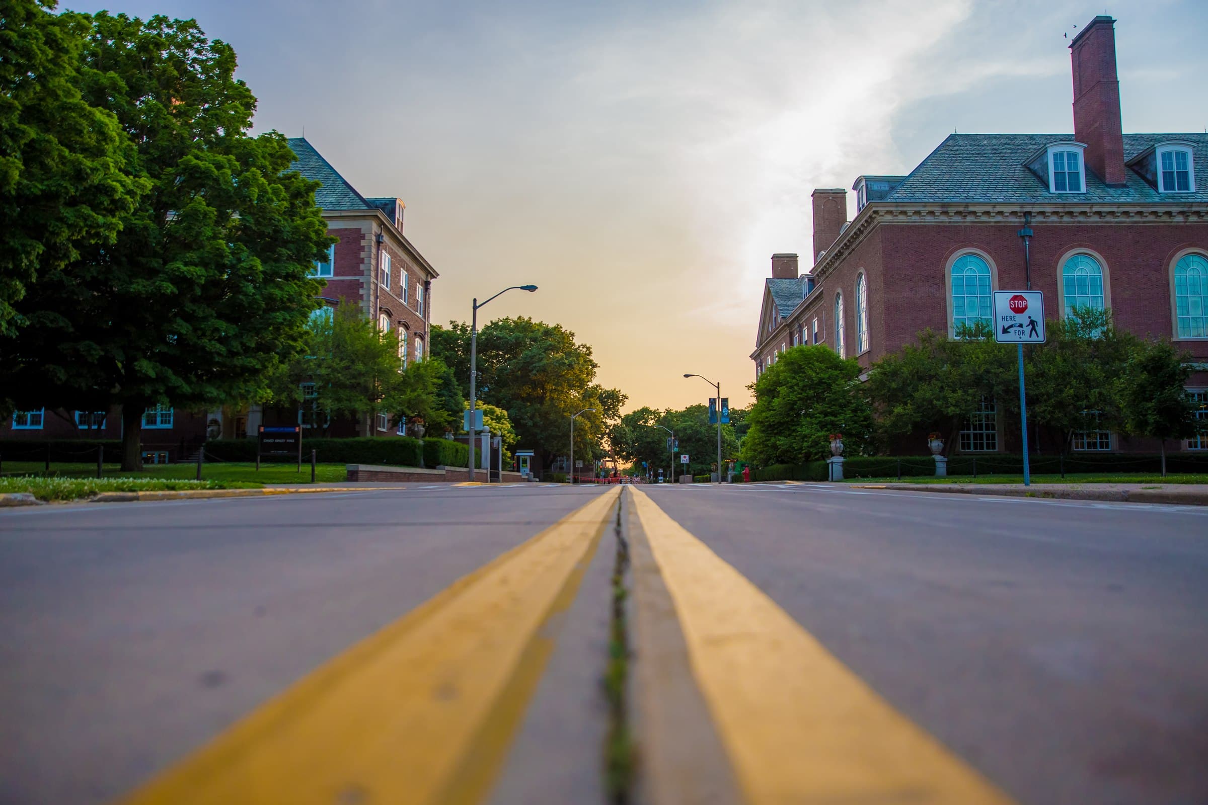 Red-brick university campus buildings along a quiet street at dusk